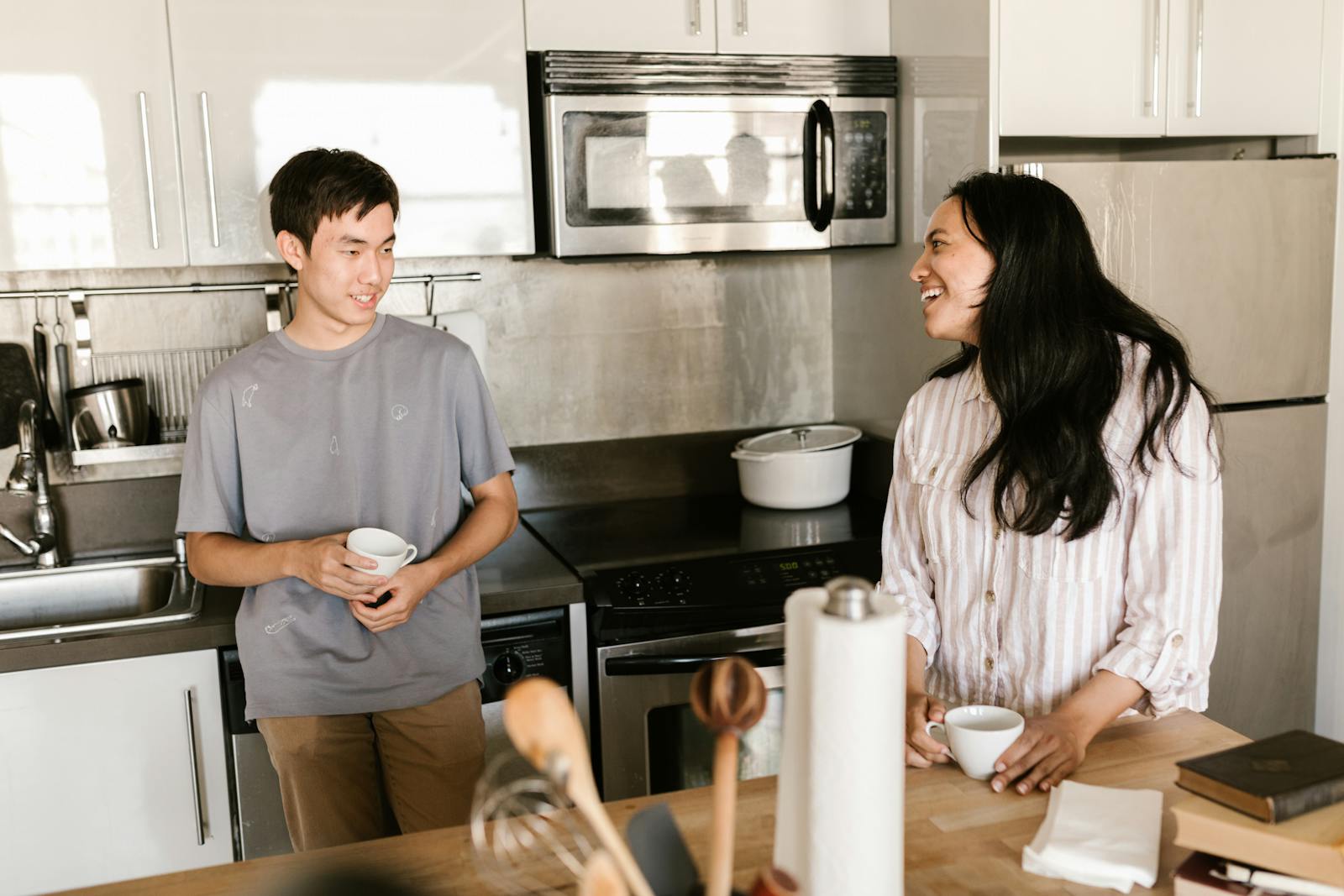 Happy friends chatting over coffee in a bright, modern kitchen setting.